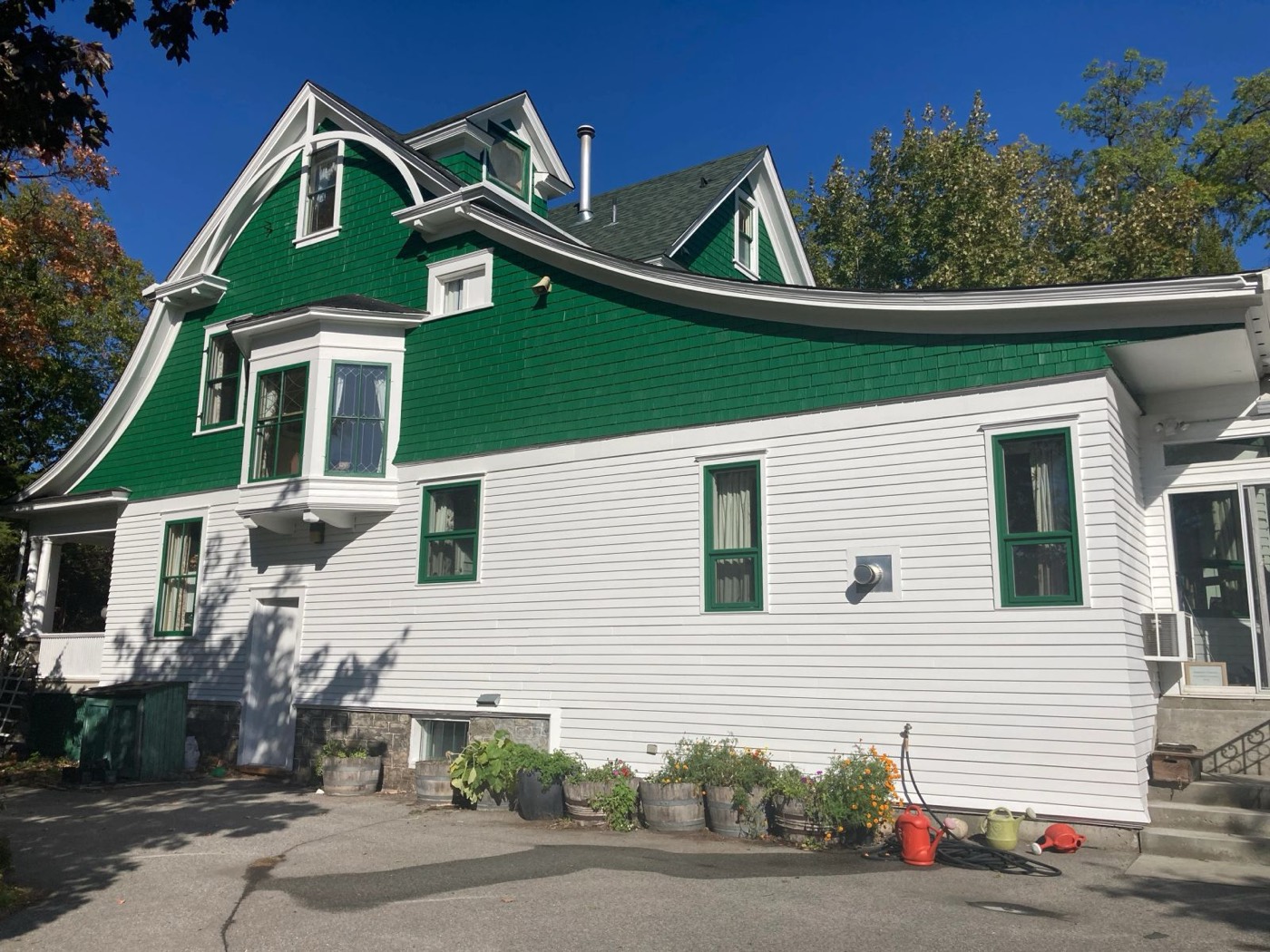Green-shingled heritage house exterior with ladders set against the gable