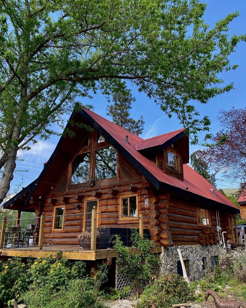 Log home with red metal roof and freshly stained log walls